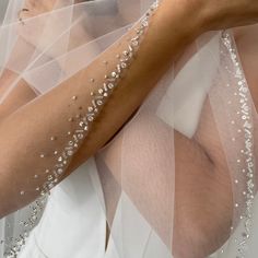 a woman in a wedding dress with her arm wrapped around the veil