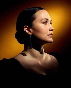 a woman with earrings on her neck looking off to the side