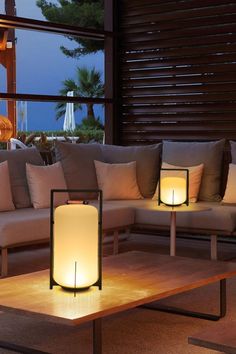 a living room filled with lots of furniture next to a large window and lit candles