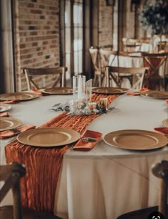 the table is set with orange napkins and place settings for an elegant dinner party