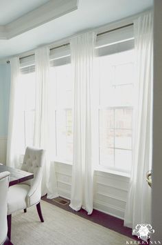 a dining room table and chairs with white curtains