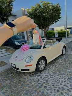 a person is holding up a pink ribbon in front of a white car