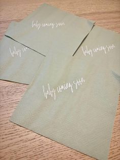 two napkins with writing on them sitting on top of a wooden table next to each other