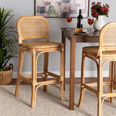 two wicker bar stools next to a small table with wine glasses on it