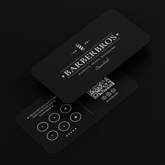 two black business cards sitting on top of each other in front of a dark background