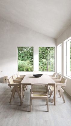 a dining room table and chairs in front of large windows