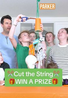 a group of people standing next to each other near a sign that says cut the string win a prize