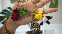 a hand holding four different key chains in it's palm, with a bird and giraffe on them