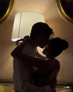 a man and woman kissing in front of a lamp