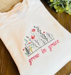 Grow in Grace embroidered Sweatshirt Fit: Unisex, Fits loose/relaxed/Crewneck Sizing: S,M,L,XL,2XL Material: 50% Cotton, 50% Polyester Thread colors are as shown *TURN AROUND TIME ~Shirts are made to order, please allow 5-7 business days to make your order (plus ship time).  *Colors and Text  We have done our best to represent colors accurately. PLEASE NOTE: Due to the hand crafted nature, and monitor displays, please expect a slight variation in colors. We will use the EXACT spelling you provide for the name. Please double check your personalization before submitting your order.  * If this is being shipped directly to the recipient I can place a small personalized note with the gift.  Please let me know what you want it to say in the check out. I don't accept returns, exchanges, or cancel Embroidered Cotton Crew T-shirt, Embroidered Cotton Crew Top, Relaxed Fit Crew T-shirt With Custom Embroidery, Custom Embroidered Relaxed Fit Crew T-shirt, Cotton Crew Top With Embroidered Text, Cotton Tops With Multicolor Embroidery And Logo, White T-shirt With Embroidered Text For Fall, Long Sleeve T-shirt With Multicolor Embroidery, Custom Embroidered Long Sleeve T-shirt