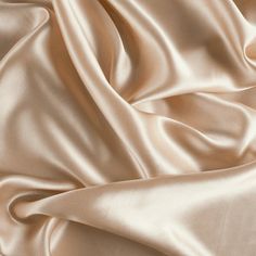 an image of a satin fabric textured with silky folds in neutral colors, closeup