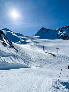 the sun shines brightly on a snowy mountain slope with ski lifts in the distance