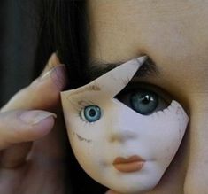 a doll being held up to its face by a woman's hand with blue eyes