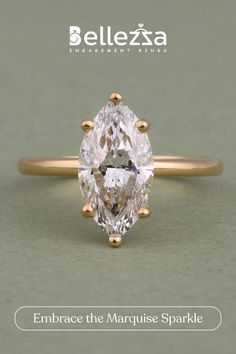 an engagement ring with a pear shaped diamond in the center, surrounded by small gold studs