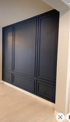 an empty room with black painted walls and wood floors