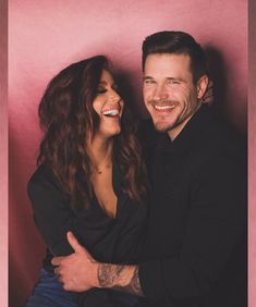 a man and woman are smiling together in front of a pink background with the caption's name on it