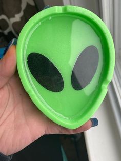 a person holding a green alien cup in their hand