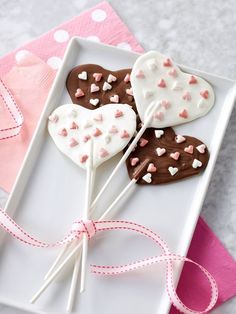 three heart shaped lollipops on a white plate