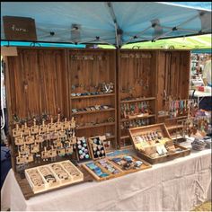 an outdoor market with wooden boxes and jewelry on display under a blue tarp covered tent