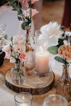 flowers and candles are sitting in vases on a table