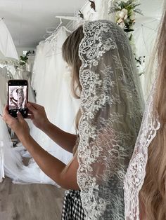 a woman in a wedding dress taking a photo with her cell phone while she is getting ready to walk down the aisle