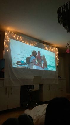 a large screen in the middle of a room with lights on it and people watching