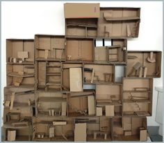 cardboard boxes stacked on top of each other in the shape of an abstract structure with furniture inside