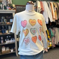 a t - shirt with hearts on it is displayed in a clothing store's window