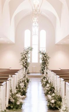 the aisle is lined with white flowers and greenery