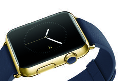 an apple watch with a blue band and gold case on the wrist, showing the time