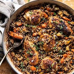 a large pot filled with food on top of a wooden table next to a spoon