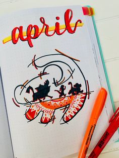 an open notebook with the word april written on it and two markers next to it