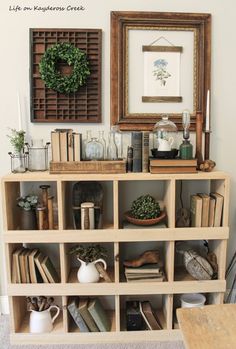 a bookshelf filled with lots of books next to a framed picture and wreath