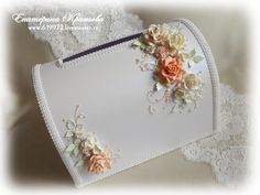 a white purse with flowers on it and lace around the edges is sitting on a table