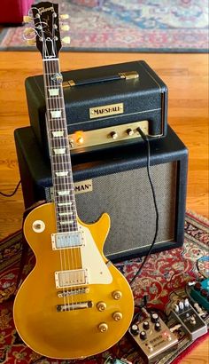 an electric guitar sitting on top of a rug next to two amps and a speaker