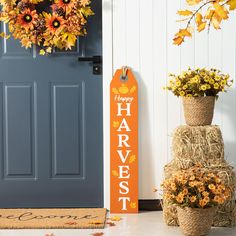 a happy harvest sign next to two fall wreaths