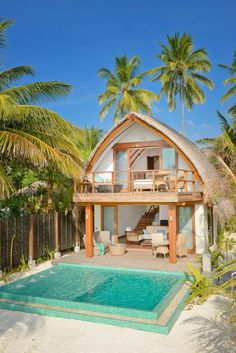 a house with a pool in front of it and palm trees around the back yard