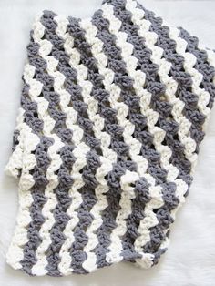 a crocheted blanket laying on top of a white furnishing covered floor