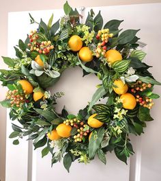 a wreath with oranges and berries hanging on the front door's white frame