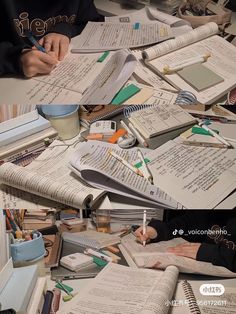 many books and papers are spread out on the table with writing utensils in them