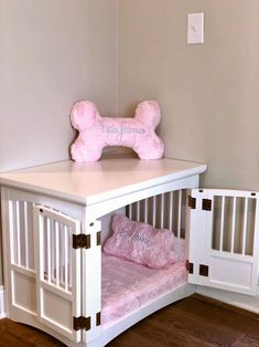 a white dog bed with a pink pillow on top of it next to a wall