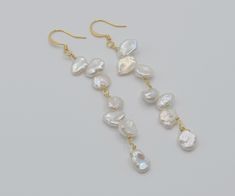 These long dangle earrings have silvery white pearls.  Keshi pearls are lustrous and iridescent.  Each pearl is as unique as a snowflake.  They are comfortably weightless.  These pearls are approximately 8 x 8 mm.  I hand select only the prettiest pearls, and I construct my jewelry to last.  They are also called cornflake pearls, petal pearls, or poppy pearls for their flat and irregular shapes. Adorned with gold plated ear wires and anti-tarnish metals. They glow against your skin which makes them beautiful for summer and the beach.  Wonderful for dress attire, formal wear, weddings and brides. Since all pearls are a different size, one earring is slightly shorter than the other which would not be noticeable. White Dangle Pearl Chain Earrings, White Drop Pearl Earrings For Party, White Long Drop Pearl Chain Earrings, White Drop Pearl Earrings, Handmade White Pearl Drop Earrings, Handmade White Drop Pearl Earrings, White Pearl Drop Dangle Earrings, White High Luster Pearl Drop Earrings, White Long Drop Pearl Earrings