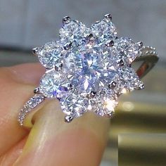 a woman's hand holding an engagement ring with two diamonds on top of it