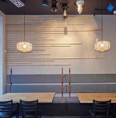 an empty restaurant with wooden tables and black chairs in front of a wall mounted light fixture