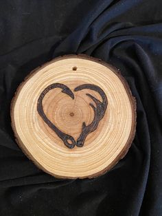 a piece of wood with a heart cut in it on a black cloth covered surface