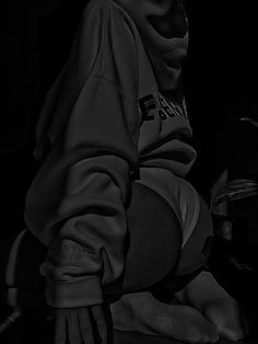 a black and white photo of a person wearing a hoodie with his hands on the ground