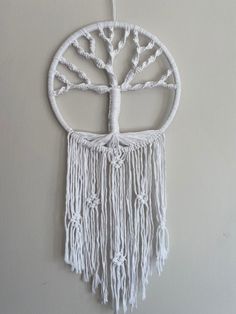 a white wall hanging with a tree of life in the center and branches on it