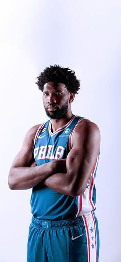 a basketball player with his arms crossed and looking at the camera while standing in front of a white background