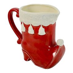 a red and white ceramic mug with tassels on the bottom is sitting in front of a white background