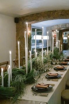 a long table is set with candles and greenery for an elegant holiday dinner party